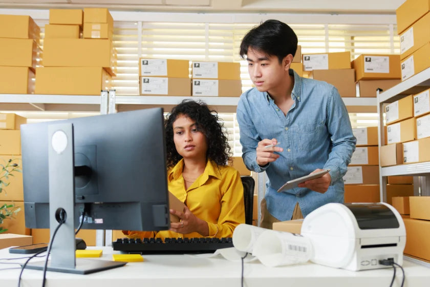 Two colleagues collaborating on a computer in a modern office setting.