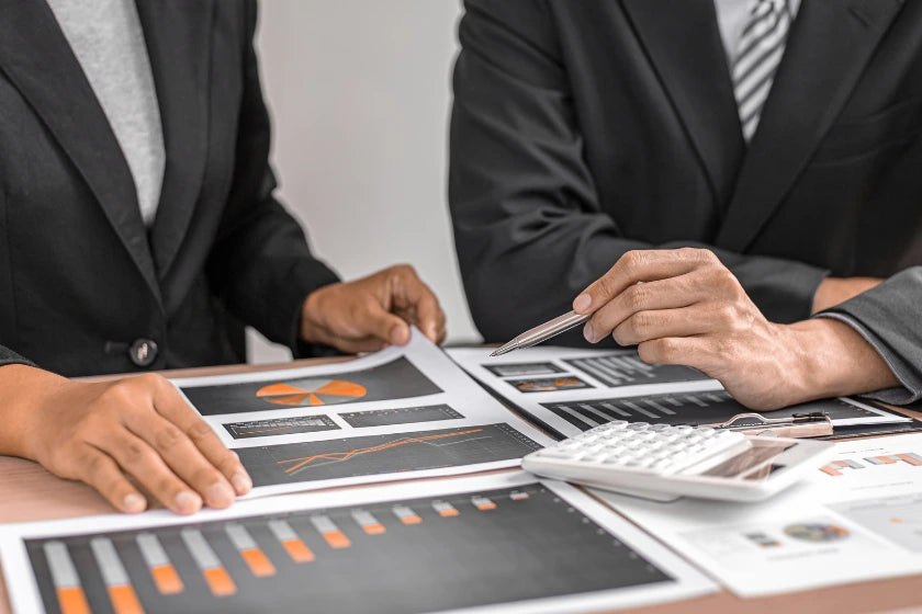 Two business professionals collaborate on a document, discussing ideas and making notes in a modern office setting.